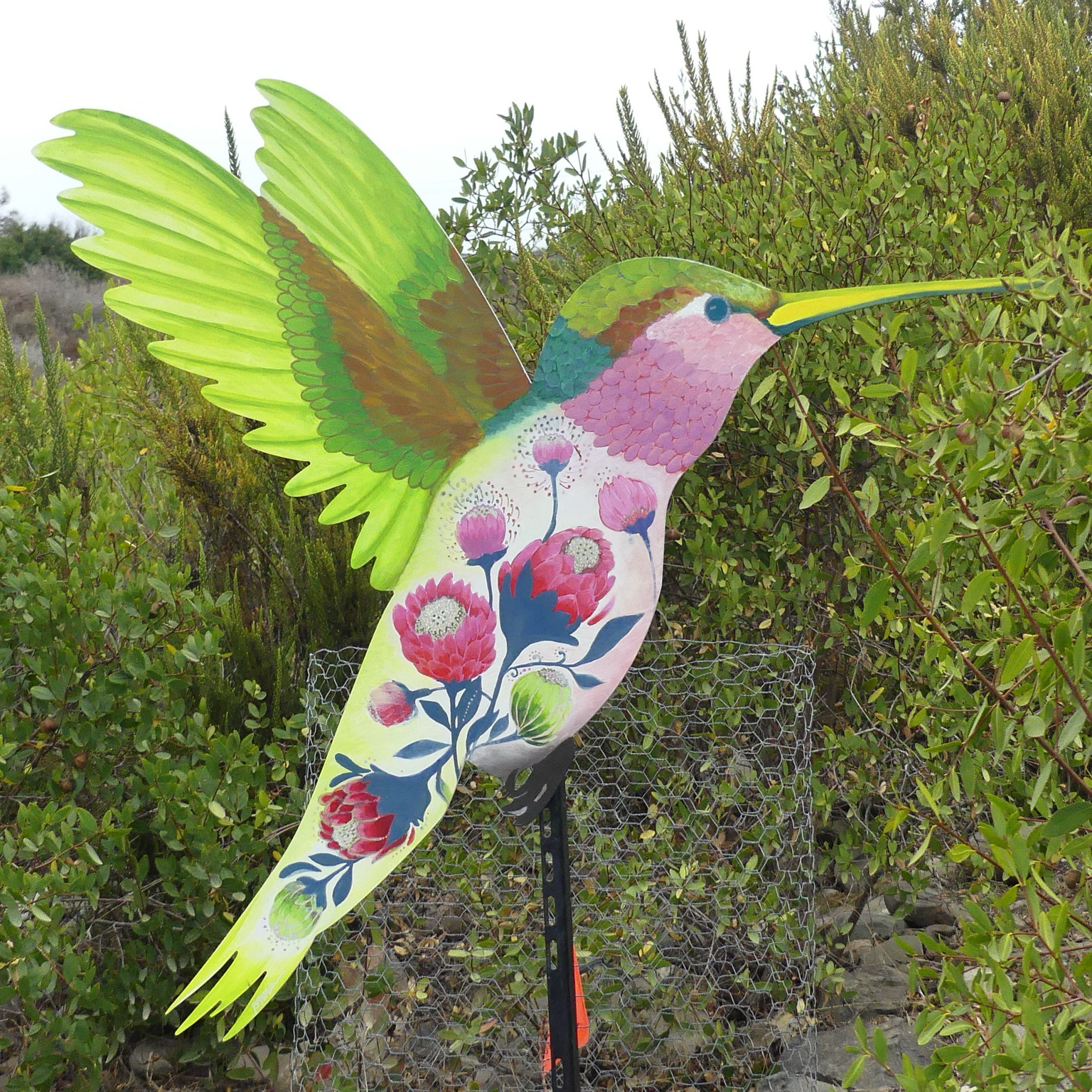 The same hummingbird cutout but with a different artist’s interpretation, pink florals on the body and green wings