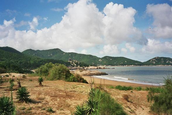 sommerliche tropische Landschaft, im Vordergrund Strand, im Hintergrund Berge